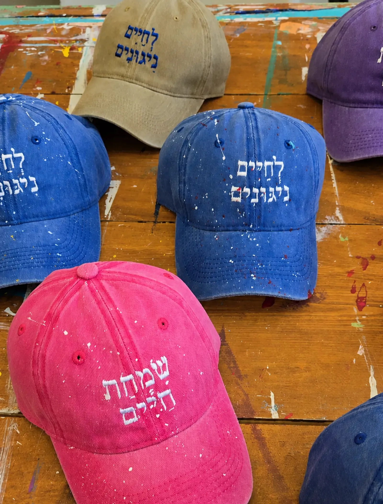 L'Chaim Nigunim embroidered caps laid out on a table